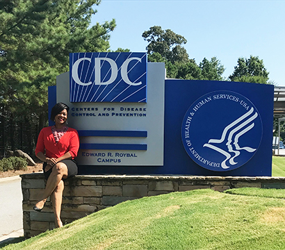 Quanza Brooks-Griffin sits in front of the CDC sign. 