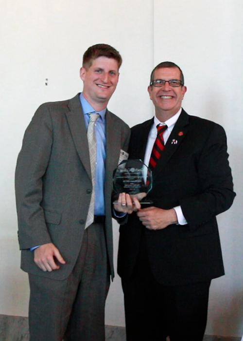 Greg Bluestein accepts Young Alumni Award from Dean Davis