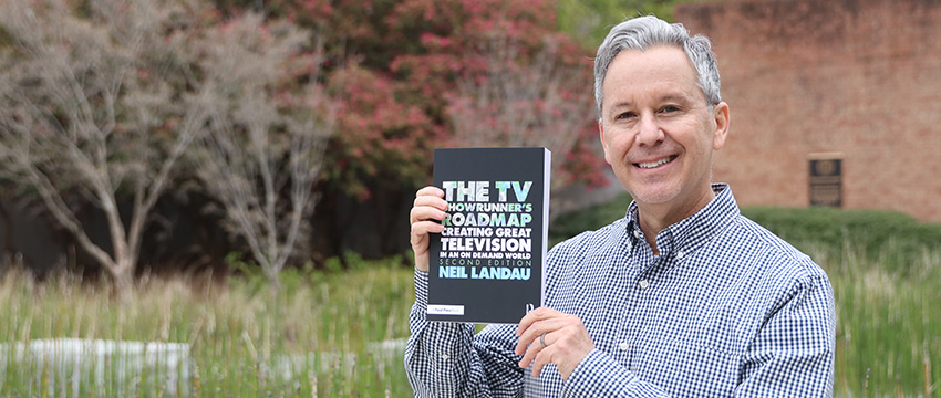 Neil Landau displays the newest edition of his book, "The TV Showrunner's Roadmap"