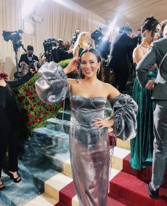 Emily poses in a silver dress, with cameras flashing on the red carpet at the 2022 Met Gala