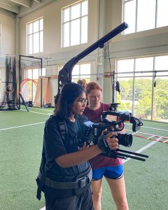 Two women in a workout facility film a scene