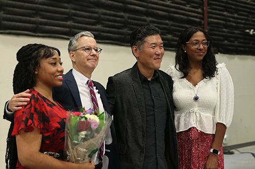 Nalani Dowling holds flowers at graduation and poses for a picture with MFA Film faculty.