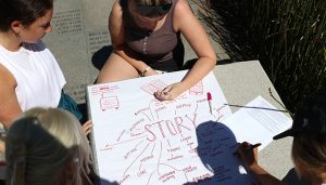 Overhead shot of students outside writing story brainstorming concepts on a large sheet of paper.