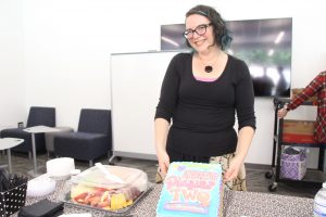 Shira Chess holding up a cake designed to look like her book Ready Player 2. 