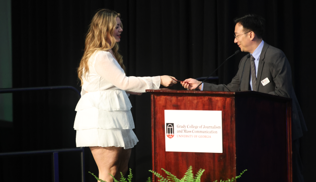 Jeong-Yeob Han takes a student's name card on stage at Grady Convocation.