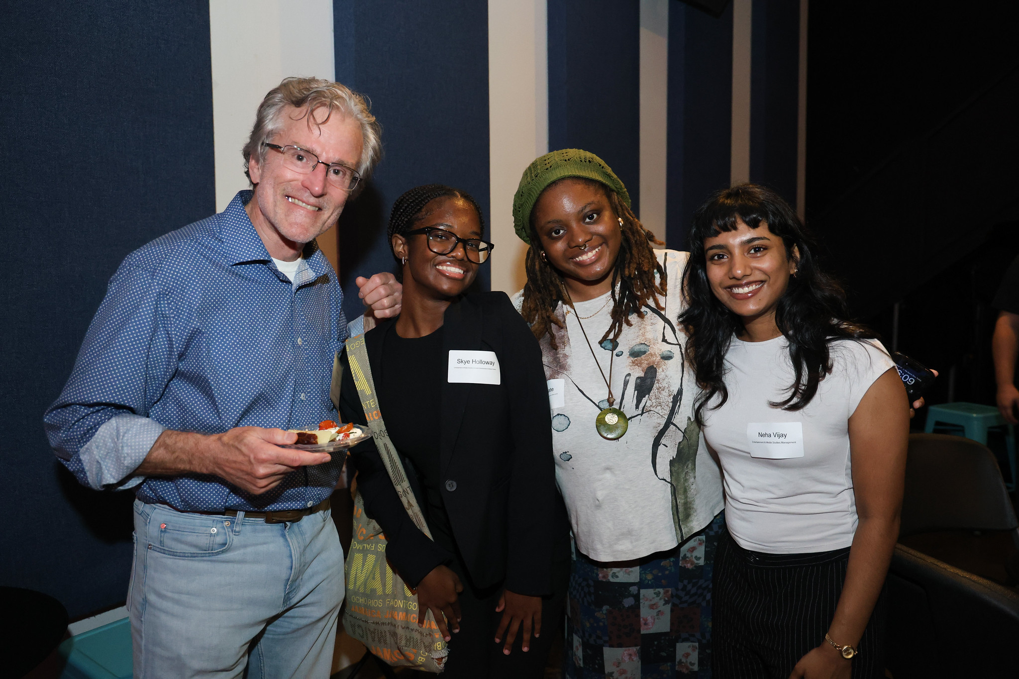 A professor and three female students pose for a picture at a networking event.