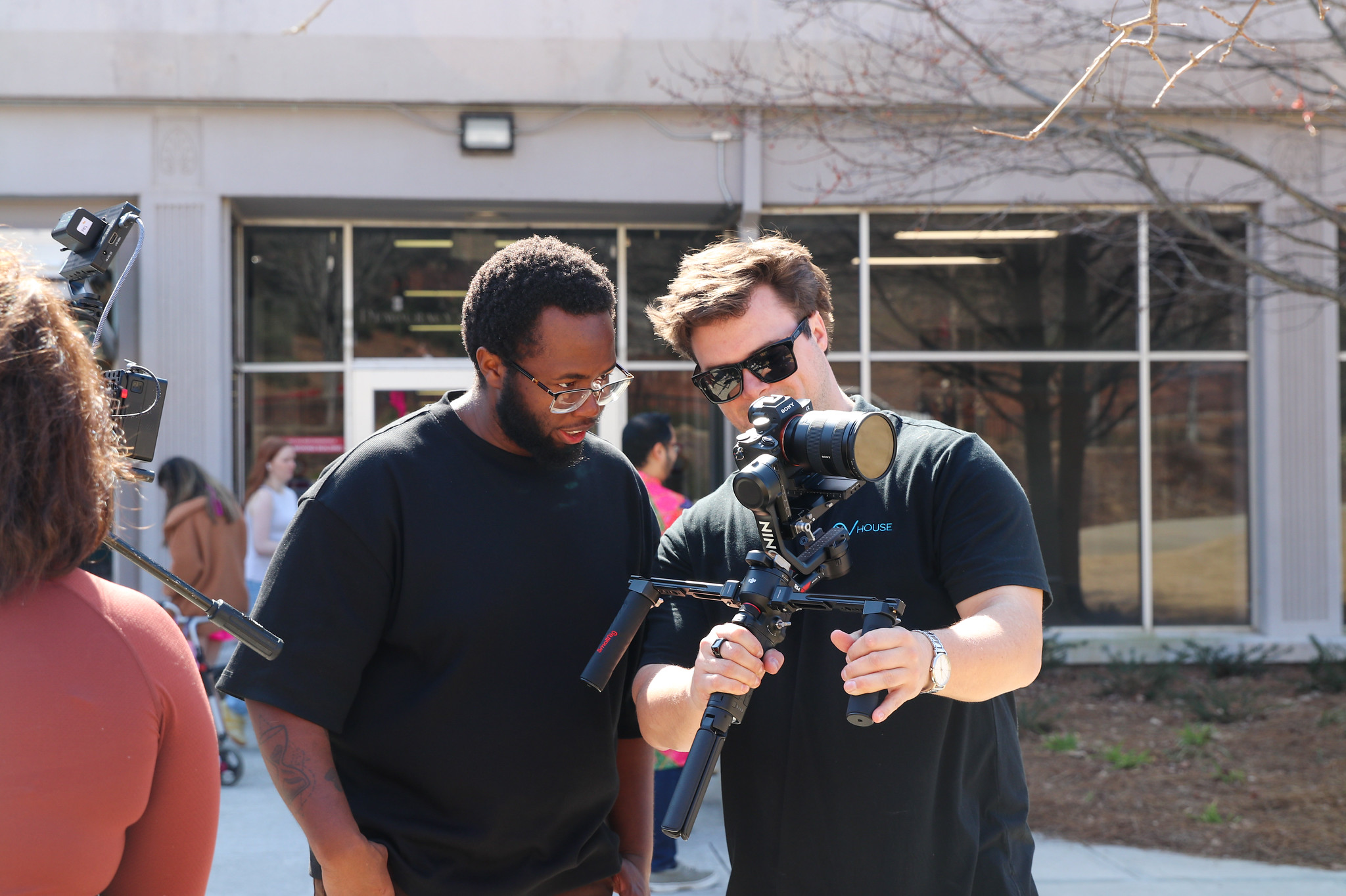 Two alumni look down at a camera at a shoot outside of Grady College.