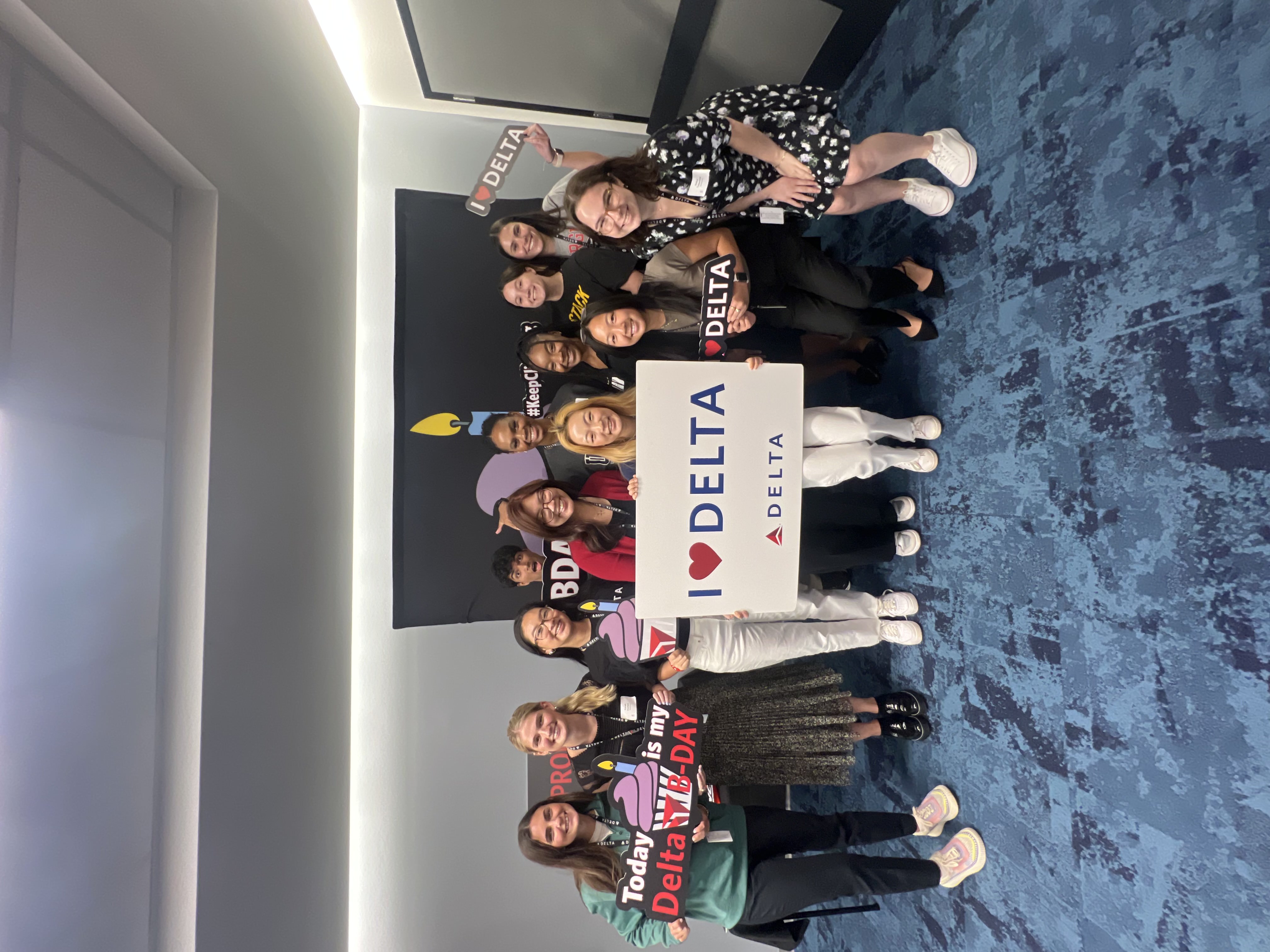 Group of people posing with a sign that reads: I love Delta