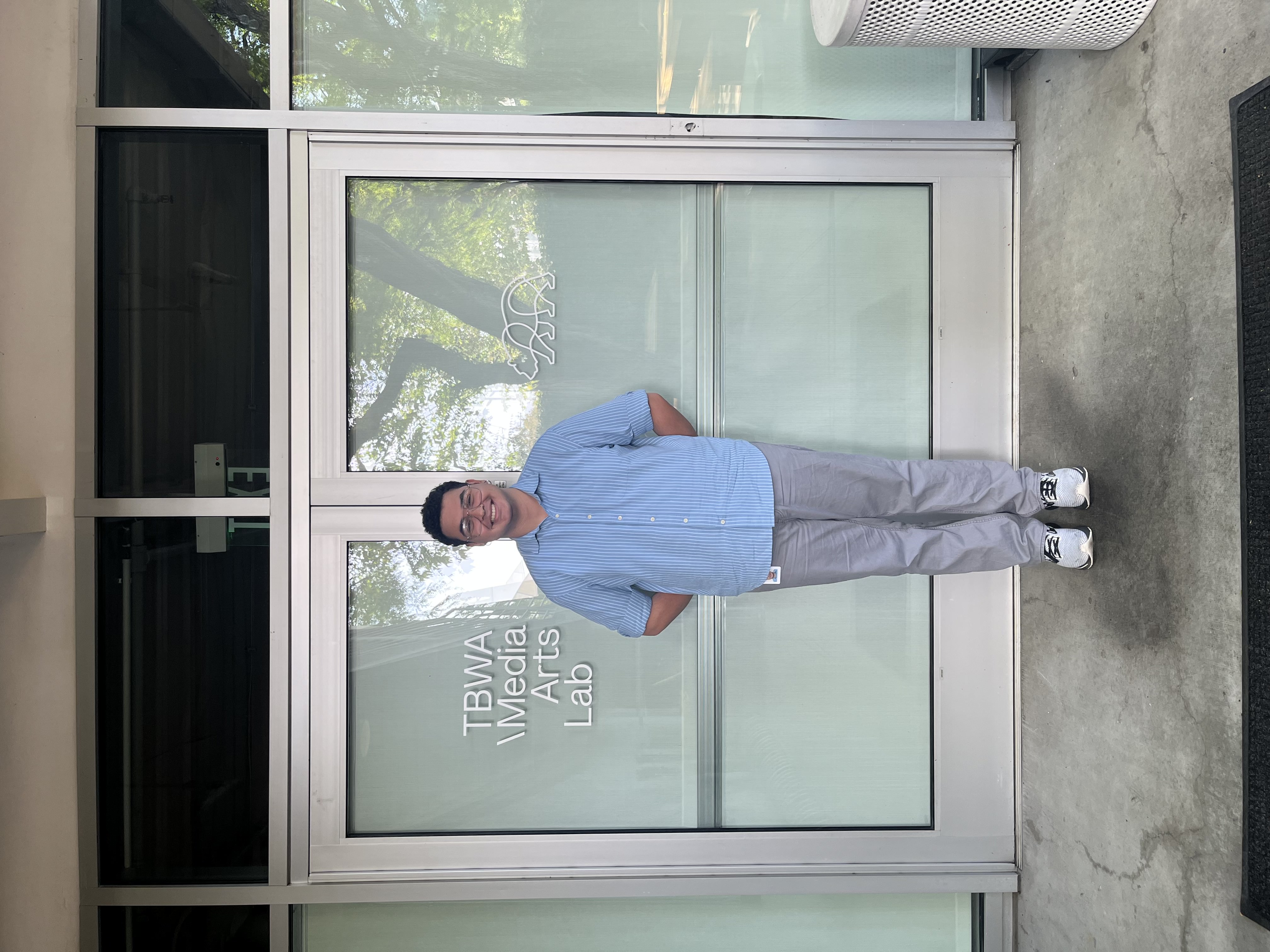 Blake Campbell stands in front of the doors to TBWA  Media Arts Lab