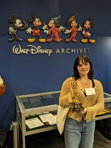 Photo of student holding an oscar in front of the walt disney archives