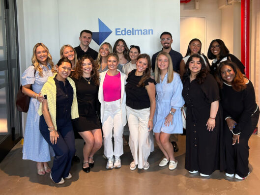 Public Relations students stand in front of an Edelman sign