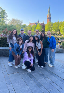 A large group of students pose for a picture in front of some Copenhagen architecture.