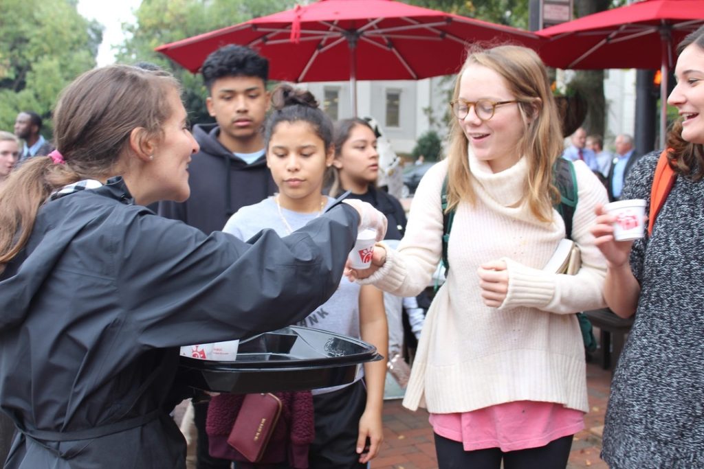 Kaitlin Febles hands a Chick-fil-A sample to a UGA student. 