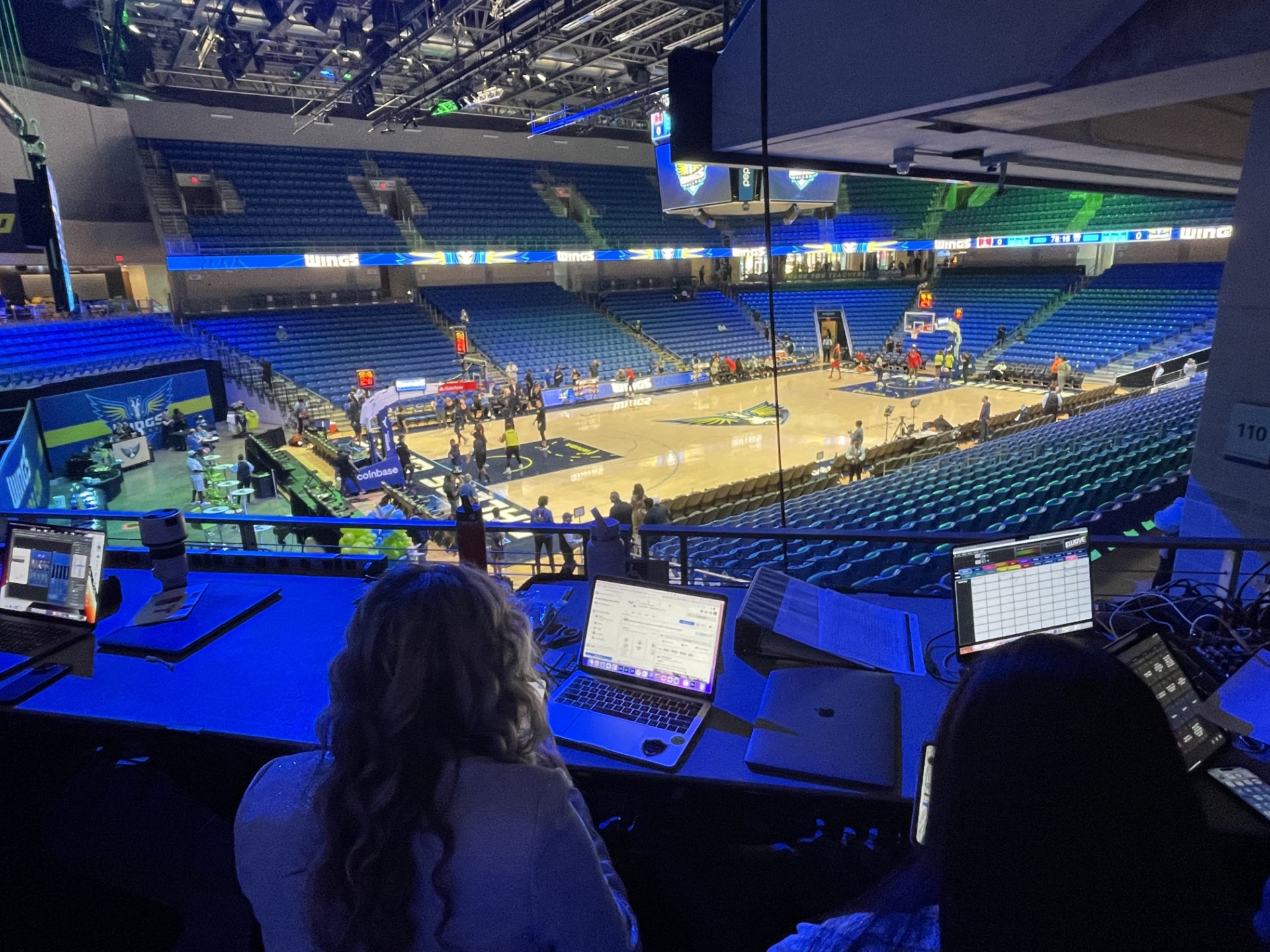 Photo of a basketball court with people sitting in a booth on their laptops