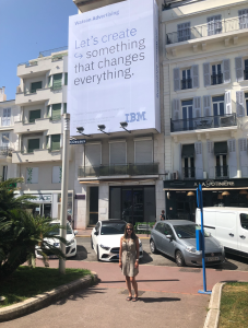 A photo of Christina Koebel standing in front of a IBM billboard in Cannes, France. 