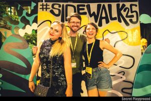 Lauren Musgrove (right) poses for a photo in front of a Sidewalk Film Festival sign with her business partner Maggie Brown and director of Yellow Wallpaper, Ricky Rhodes. 