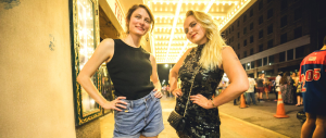 Lauren Musgrove (left) and Maggie Brown stand under the theater lights outside, posing for a photo.