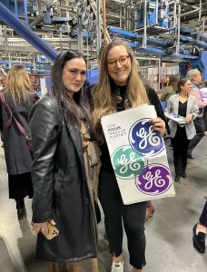 Two women posing with a GE poster. 