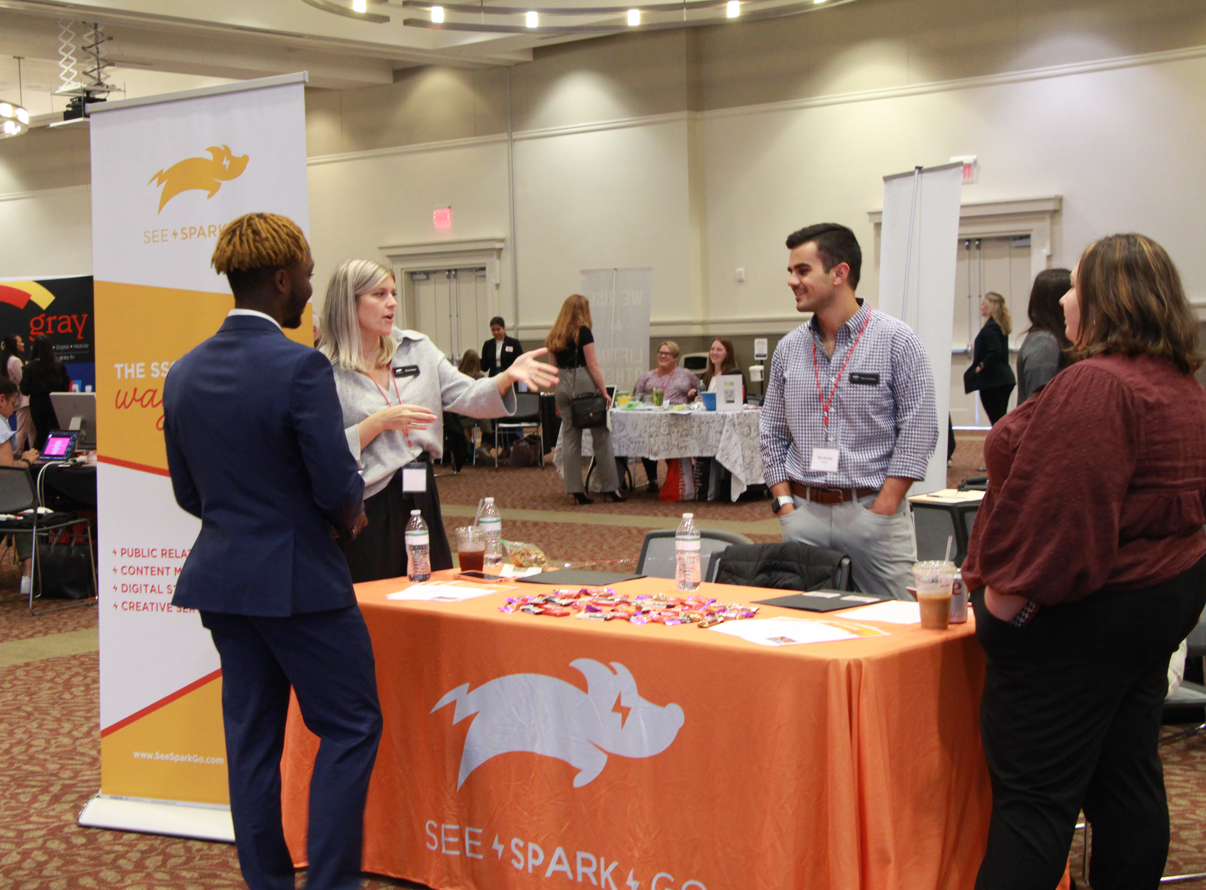 Student network with prospective employers at an orange See Spark Go table.
