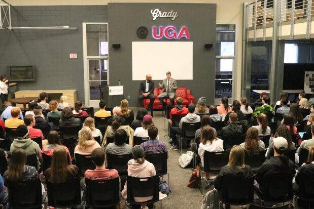 A crowd of students listens to a lecture in Studio 100.