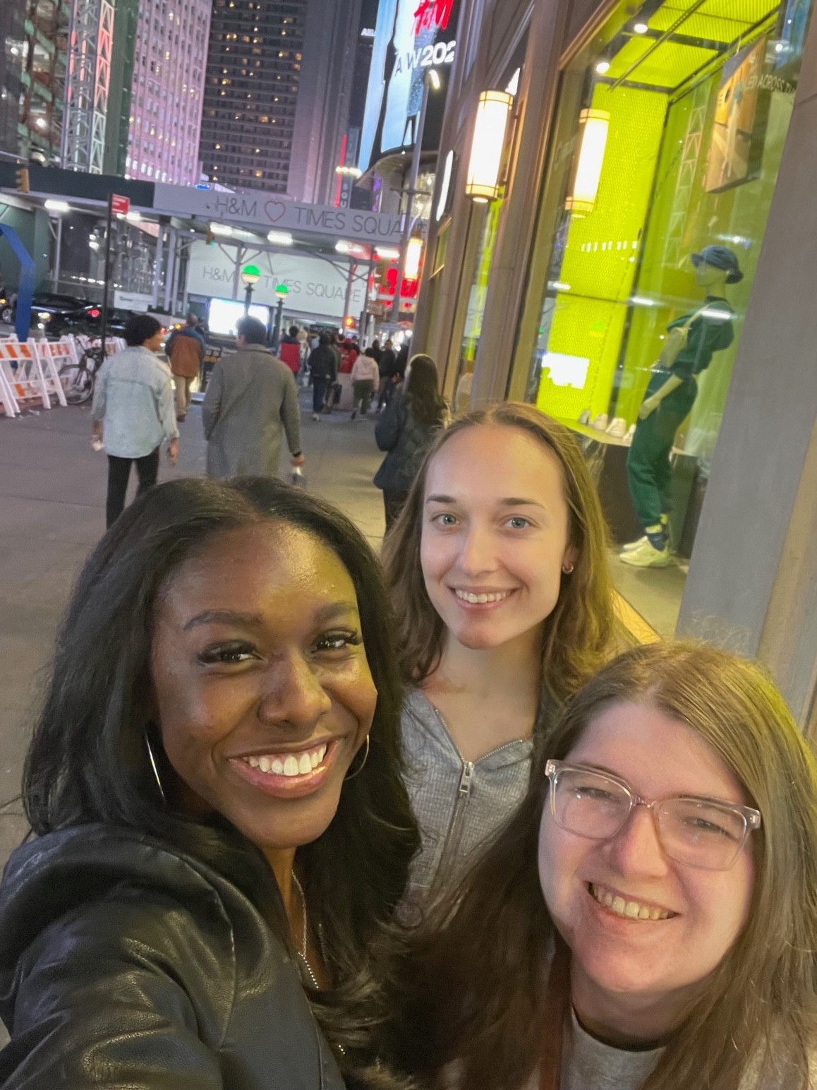 Three students stand in Time Square.