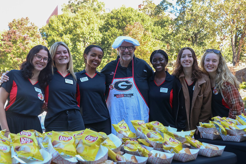 Dean Davis with a sgroup of Grady Ambassadors on the Schnitzer Family Media Lawn. They are standing in front of a table that has many bags of Lays potato chips.