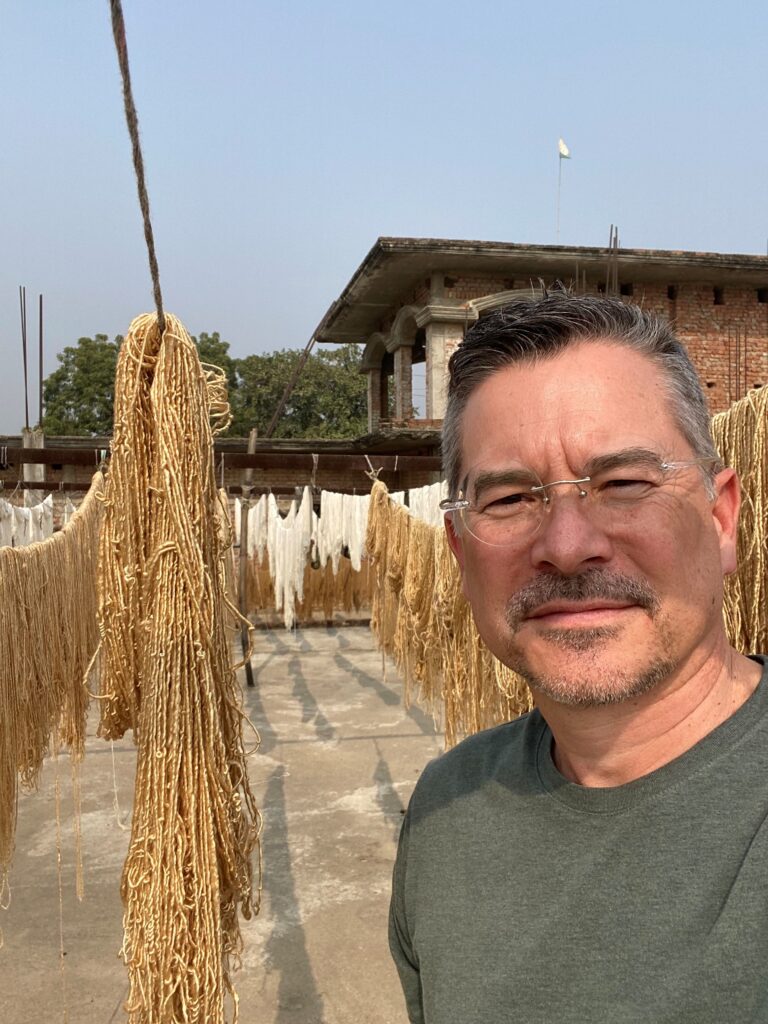Etheridge posing in front of yarn in India.