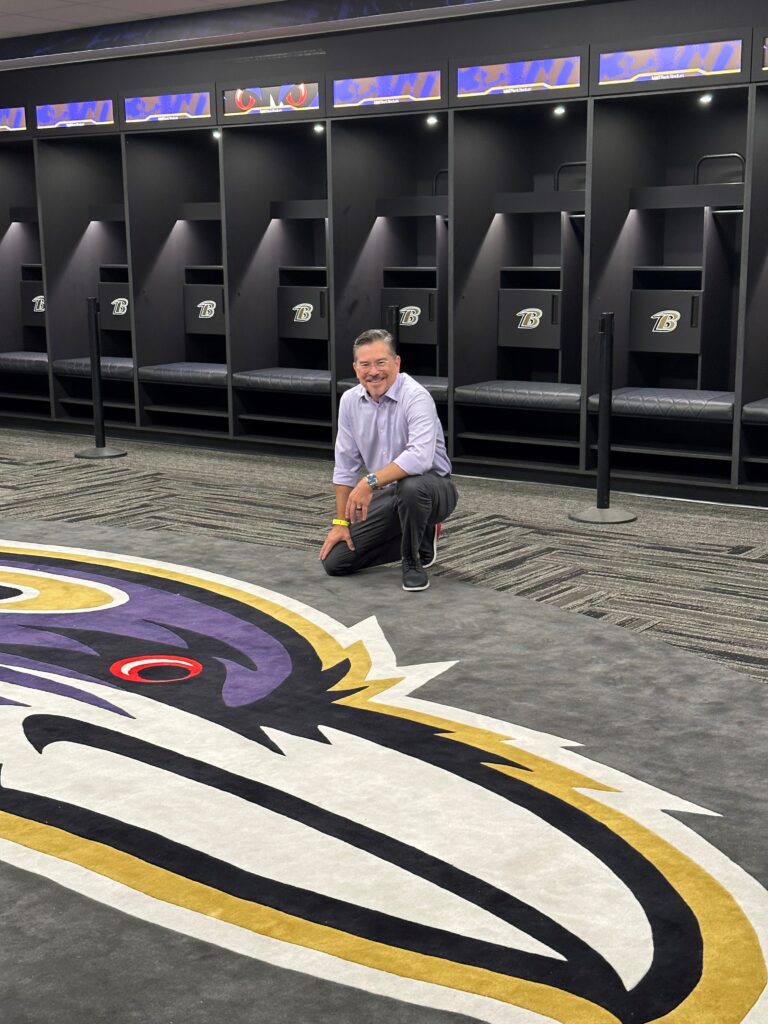 Etheridge posing with the Baltimore Ravens custom rug