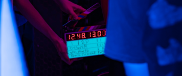 A clapperboard about to be clapped on a movie set. The clapperboard has Win Marks' name on it.