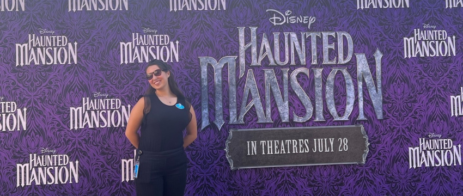 A student poses in front of a banner for Disney's Haunted Mansion movie.