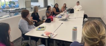 A group of Fink Fellow students sit in a round-table style discussion with Professor Lori Johnston in a Grady College room for their first meeting of the semester.