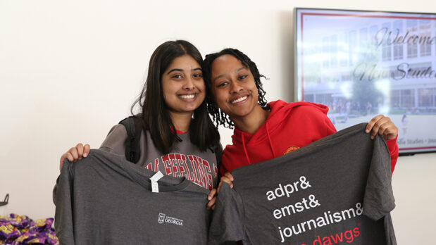 Two students hold up their Grady College tshirts.