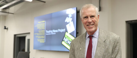 Richard T. Griffiths stands in front of a Trusting News graphic in the Grady Newsource space.