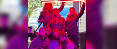 Group of people holding a long, red light.