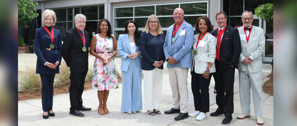 Salutes honorees wear their medals and hold awards in front of Grady College.