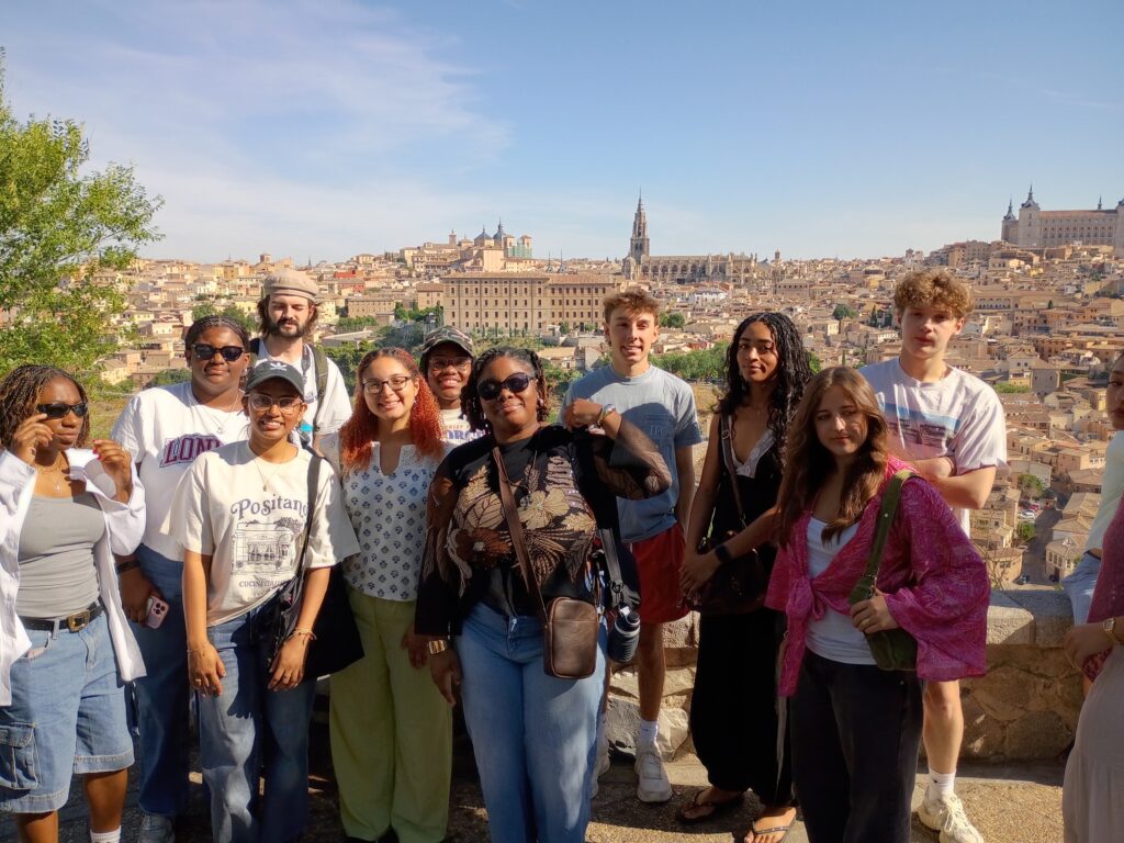 A large group of students in an elevated area overlooking a Spanish City.