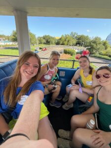 Four women ride on a Disney Peoplemover cart.