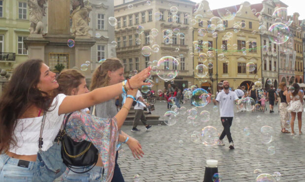 Girls reaching for bubbles in town square in Prague