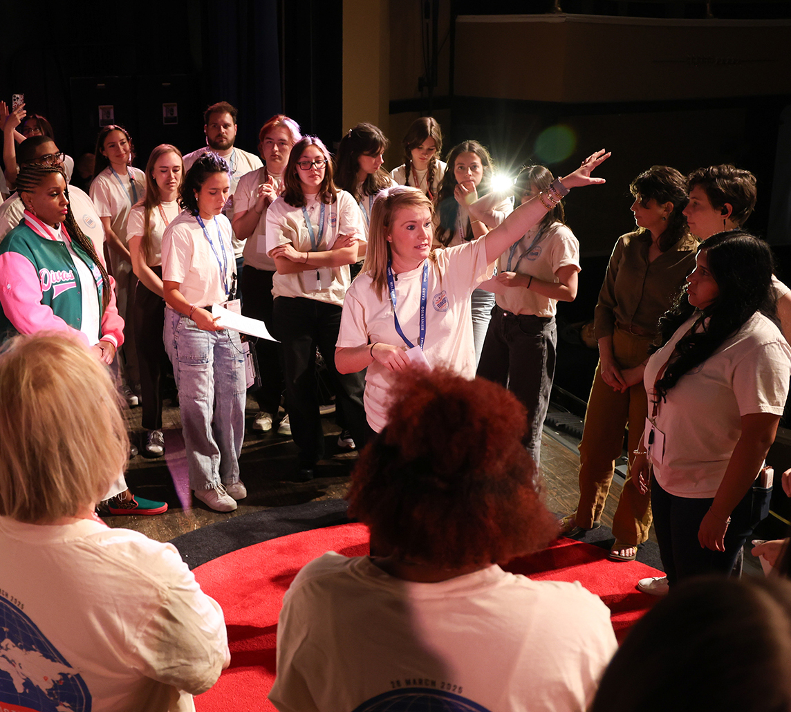 Megan Ward points off stage as students surround her.