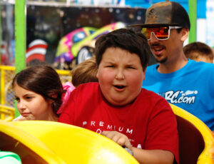 A boy grimaces as he enjoys a ride at the fair.