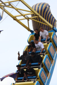 A group of people scream as they ride a giant swing at the fair.