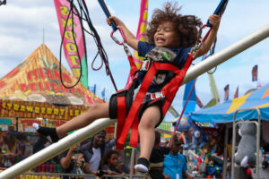 A child smiles as he is on a bungee jump at the fair.