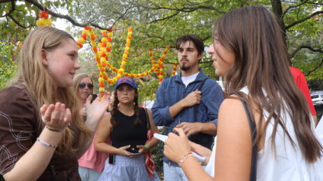 Students stand in a circle interviewing event participants.