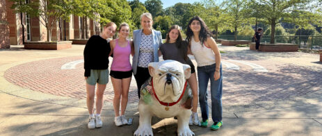 A group of women pose for a picture behind a bulldog statue.