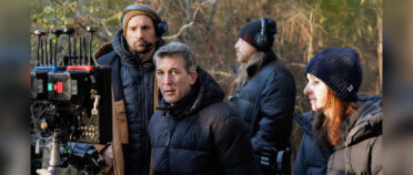 A group of people on a film set. Some have headphones on there is a film monitor in the foreground.