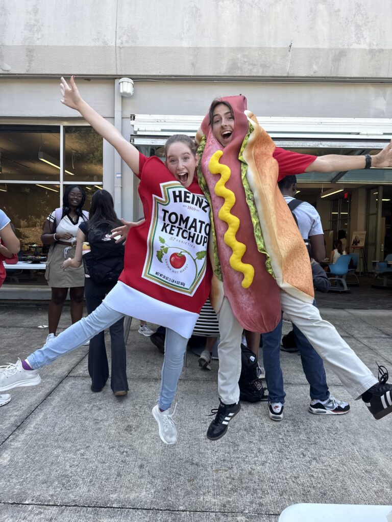 Carter Lemelin is dressed up in a hot dog costume and is jumping next to a friend in a tomato bottle costume.