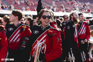 Carter Lemelin smiles in his Redcoat Band uniform on the field of Sanford Stadium amongst other members of the Redcoat Band.