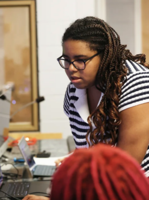 Profile of Sabrina Felix as she leans over tech board.