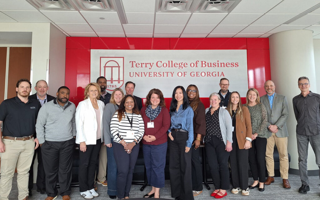 A group of people pose for a picture in front of sign that reads Terry College of Business.