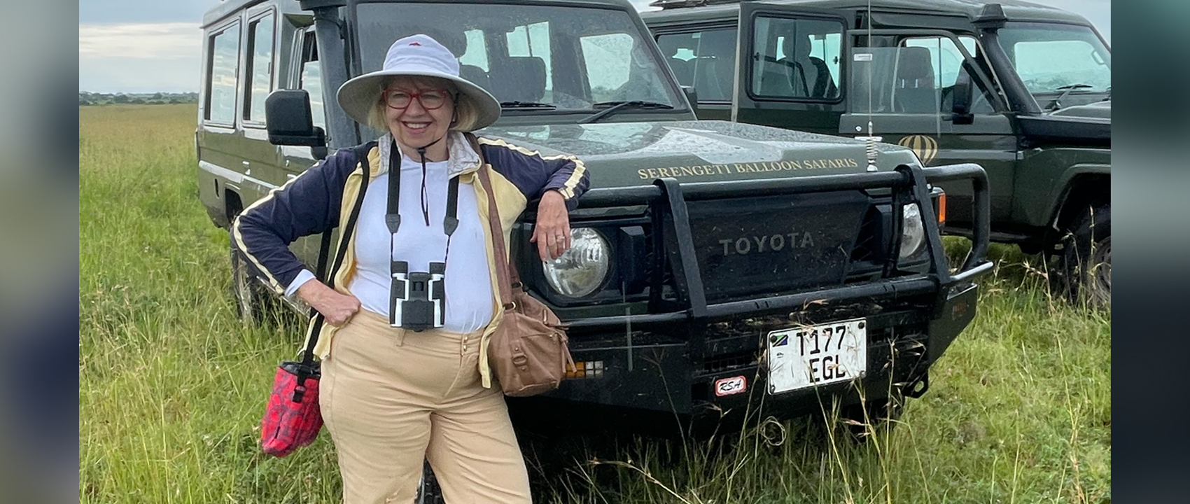 Carolyn Tieger stands in front of a jeep in Tanzania.